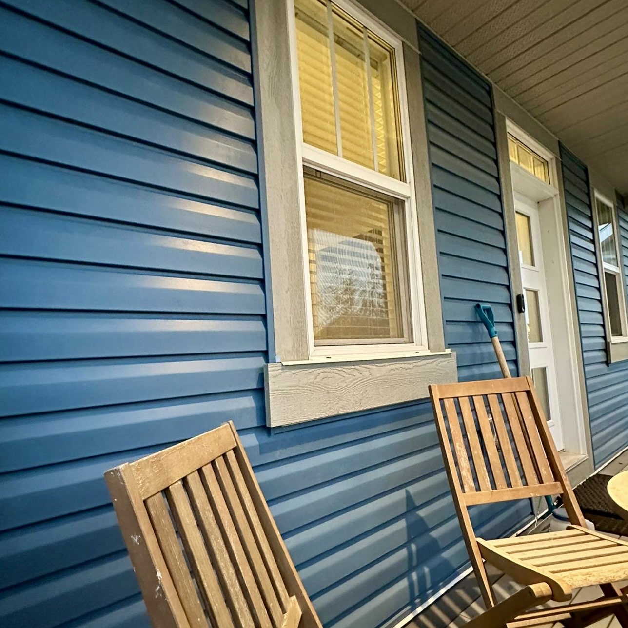 Close detail of blue vinyl lap siding, trim and window surround on the covered porch