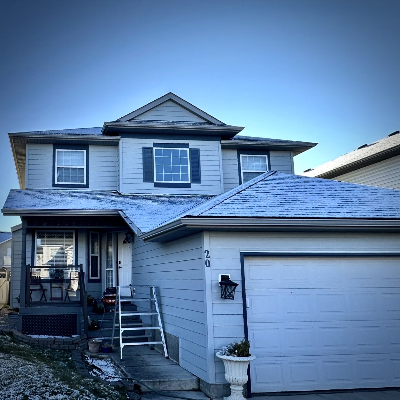 Front-to-back exterior on a two-storey: new shingles, grey lap siding, and white soffit and fascia along the full roofline.