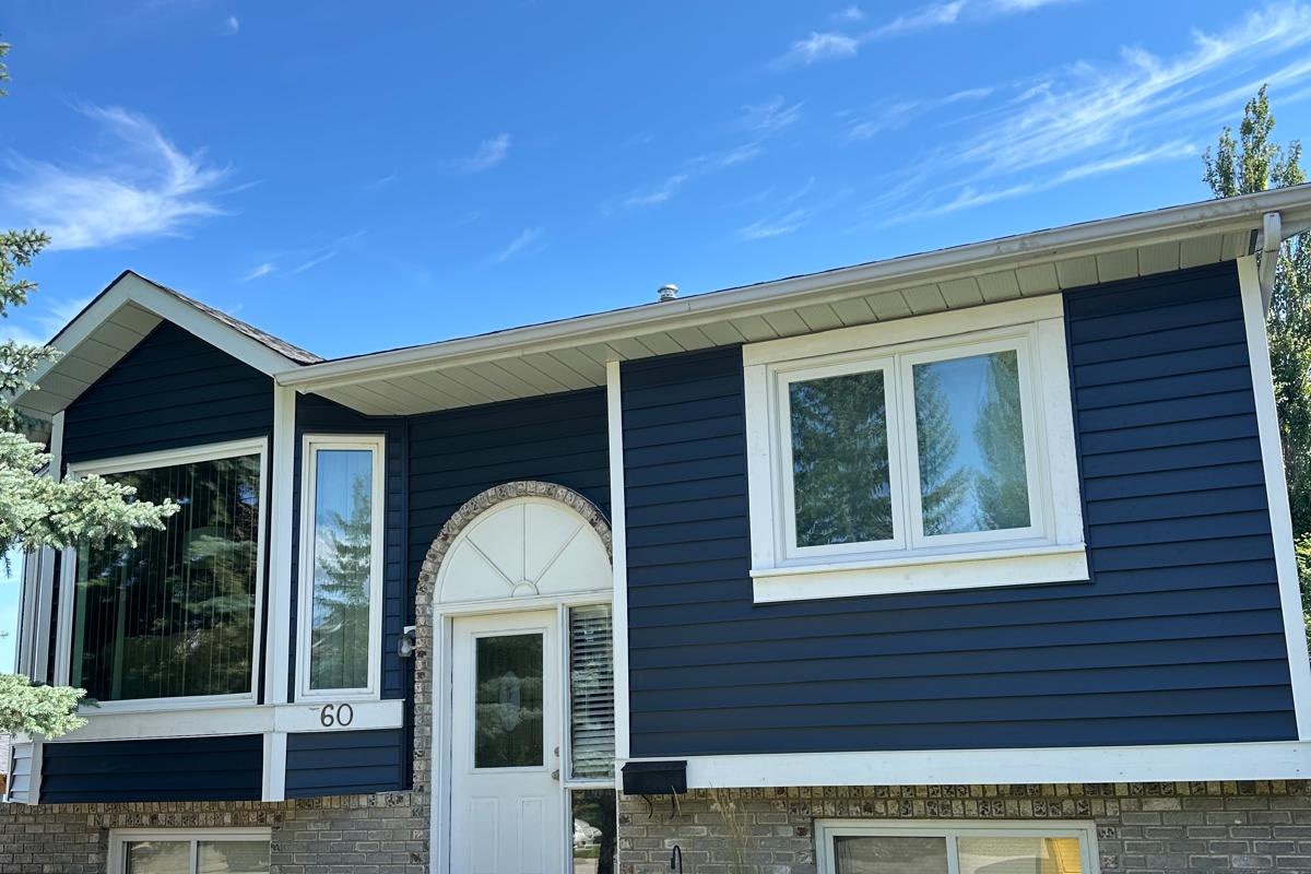 Bi-level re-sided in deep navy lap siding with wide white trim carried over the original brick base.