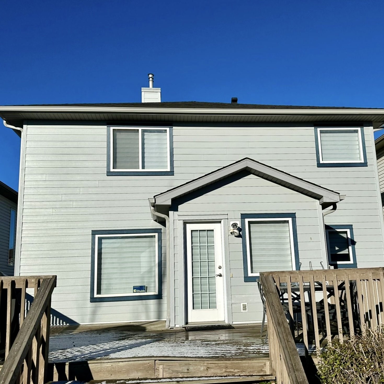 Rear elevation of a Calgary home with new grey siding, white soffit and fascia along the roofline