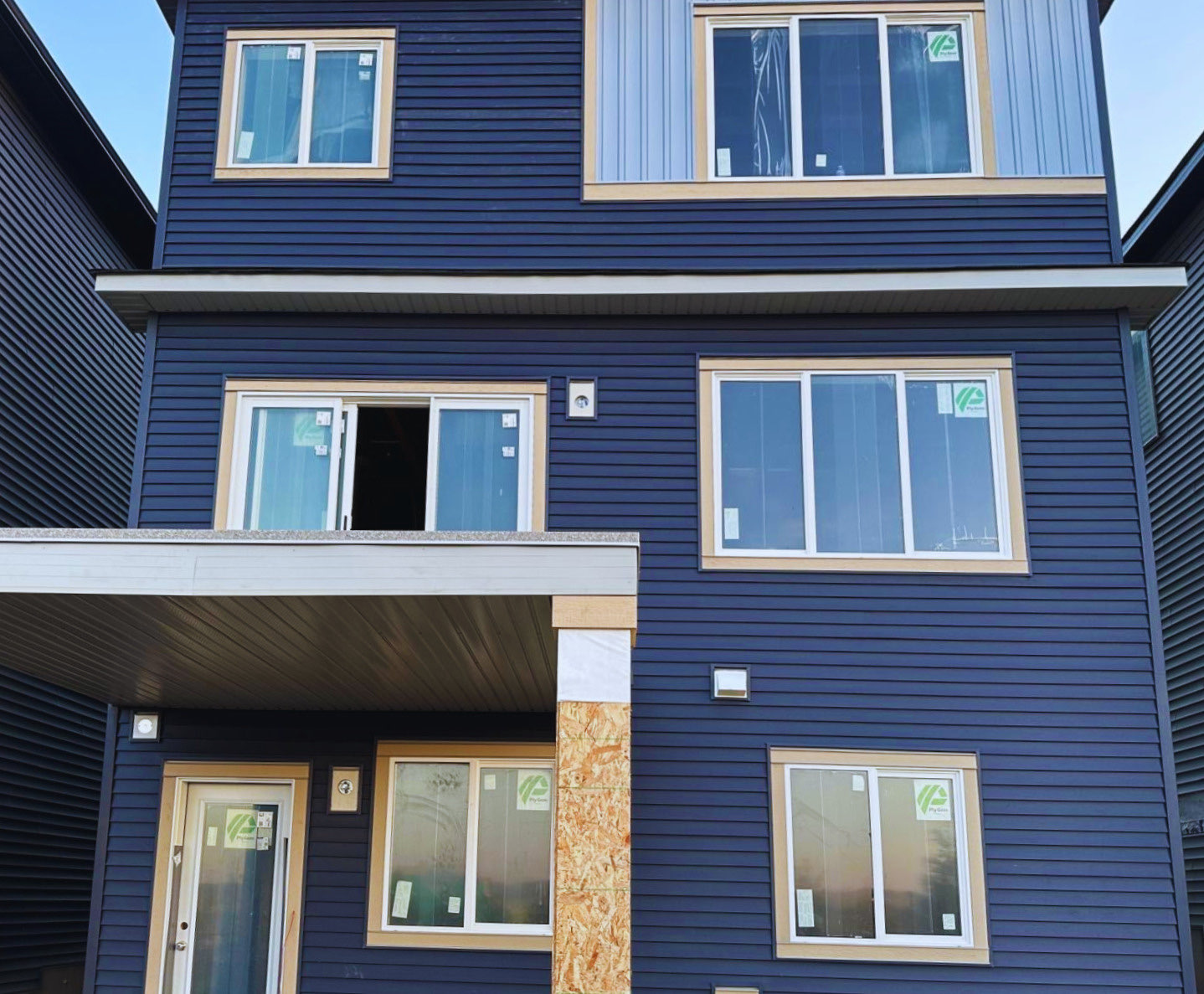Three-storey Calgary new build in dark blue siding with light vertical architectural accent panel